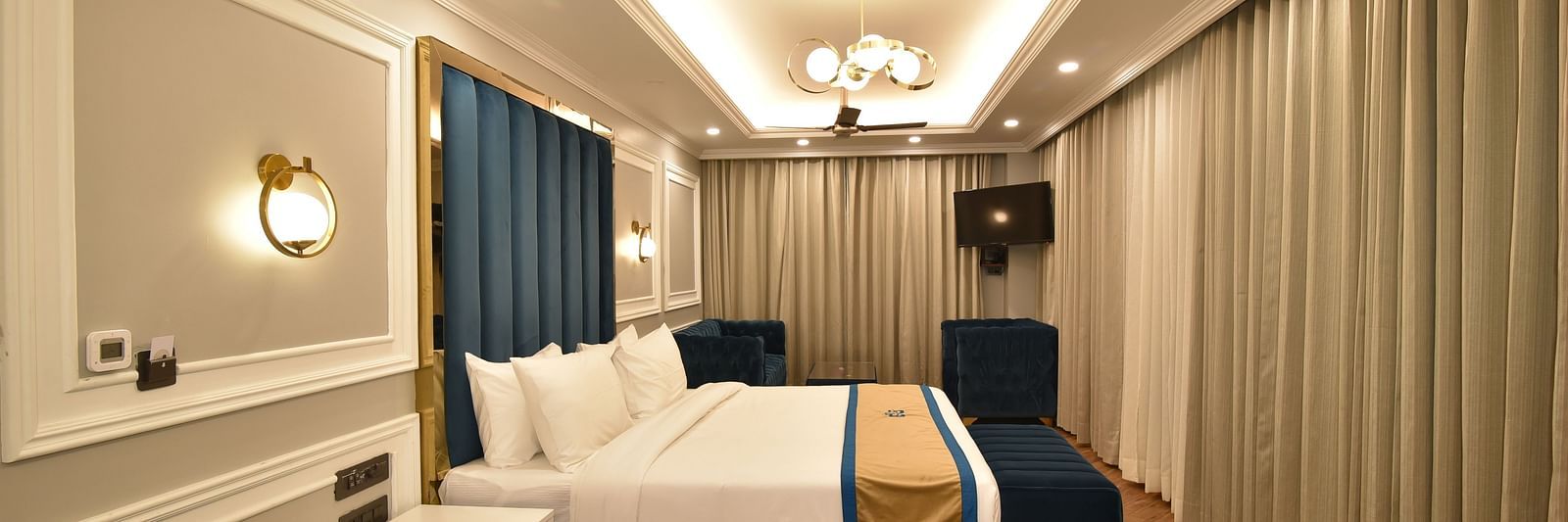 A spacious hotel room with a large bed, contemporary decor, and a cosy seating area. Large windows allow natural light and offer scenic mountain views.