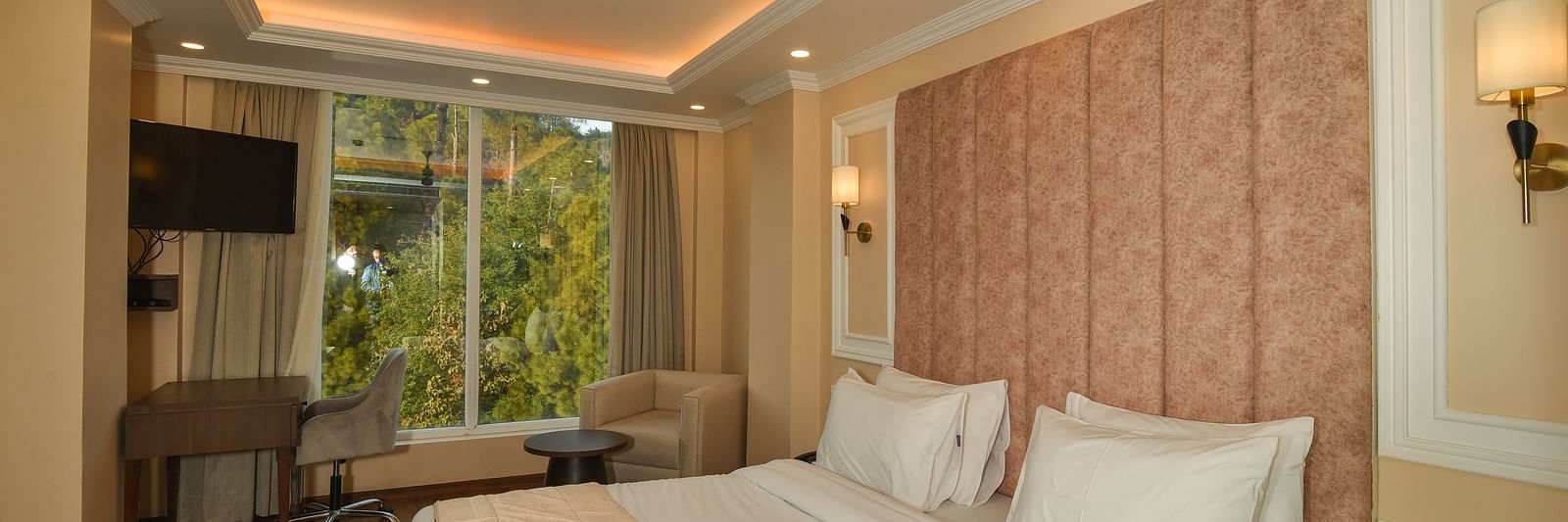  A bright and spacious hotel bedroom with a large bed, soft lighting, and large windows offering scenic mountain views.