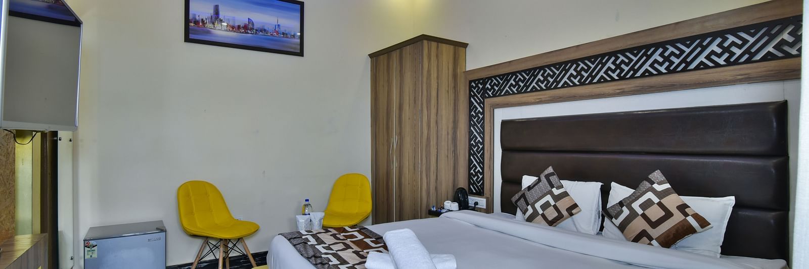 A Deluxe Room at DLS Dalhousie Valley Resort with a  king size bed and two yellow chairs