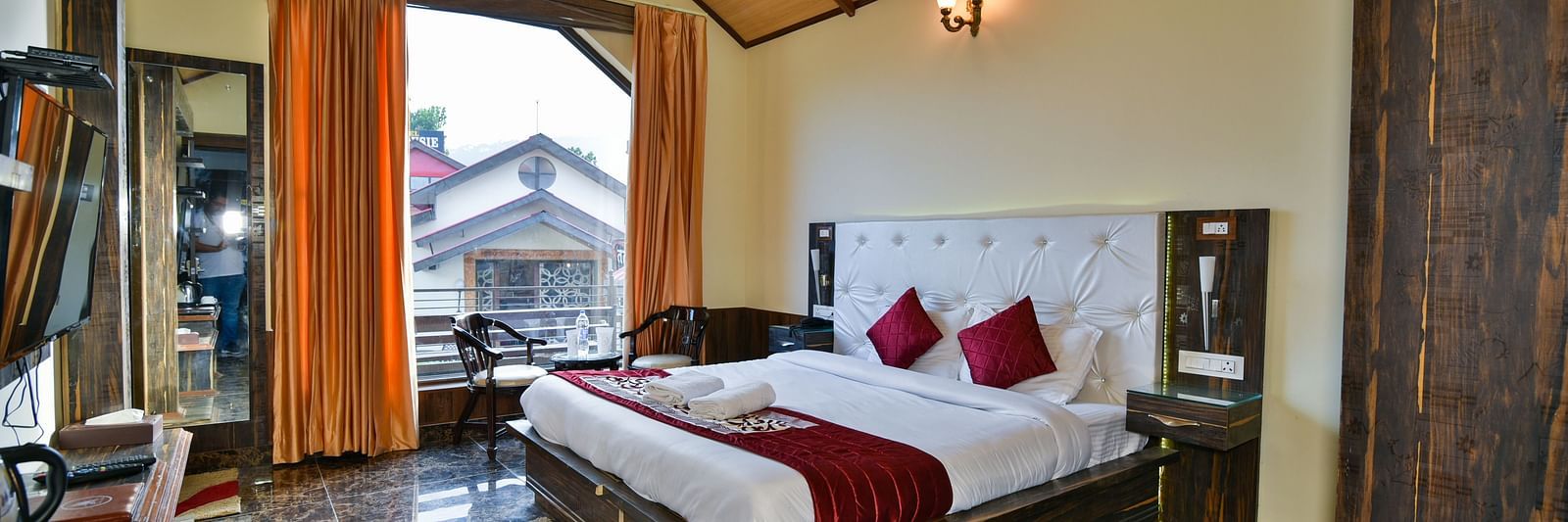 A Deluxe Room at DLS Dalhousie Valley Resort with a  king size bed, TV and a balcony 