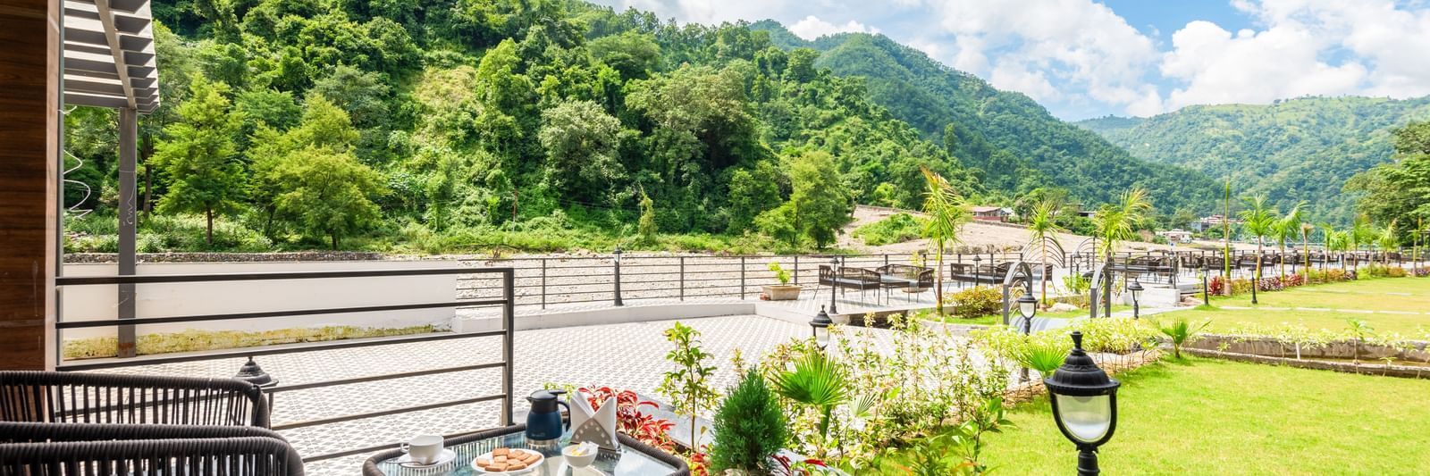 Closeup view of the balcony of Luxury Cottage at DLS Divine Resort and Spa featuring lush green garden area with chairs and tables