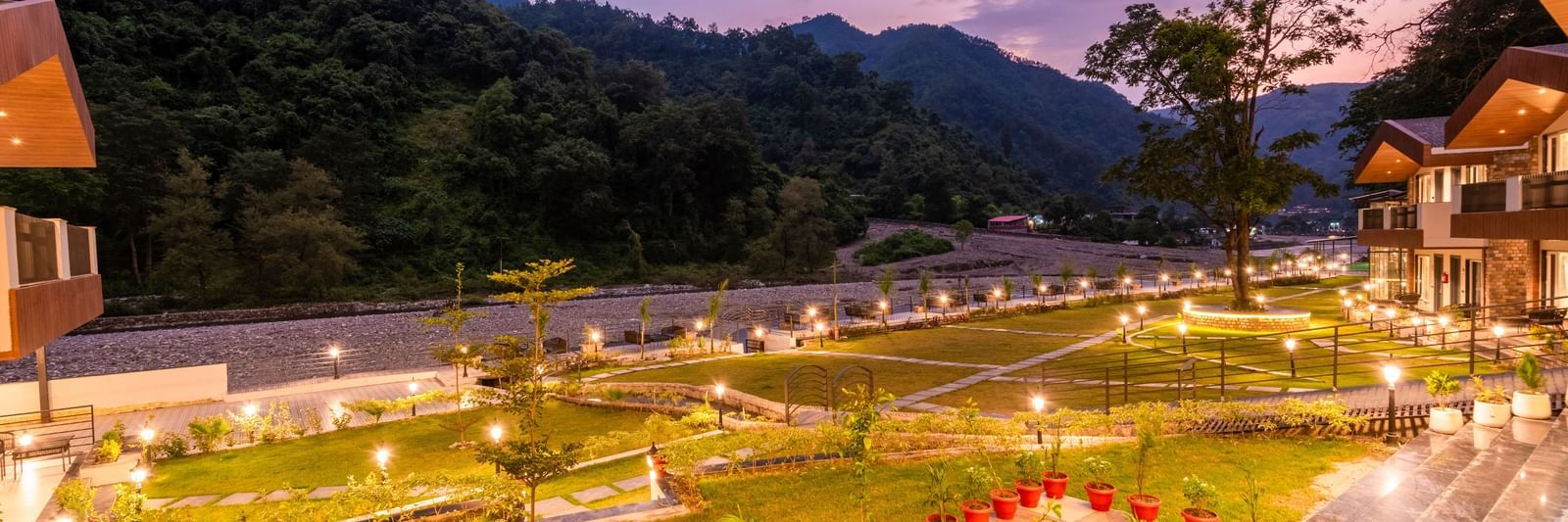 Garden area at DLS Divine River Resort and Spa featuring lush green grass and flower pots.