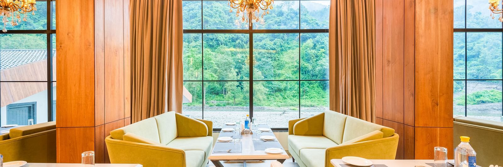 Restaurant at DLS Divine River Resort and Spa  with seating arrangement, large window, chandelier, and ambient lighting. 