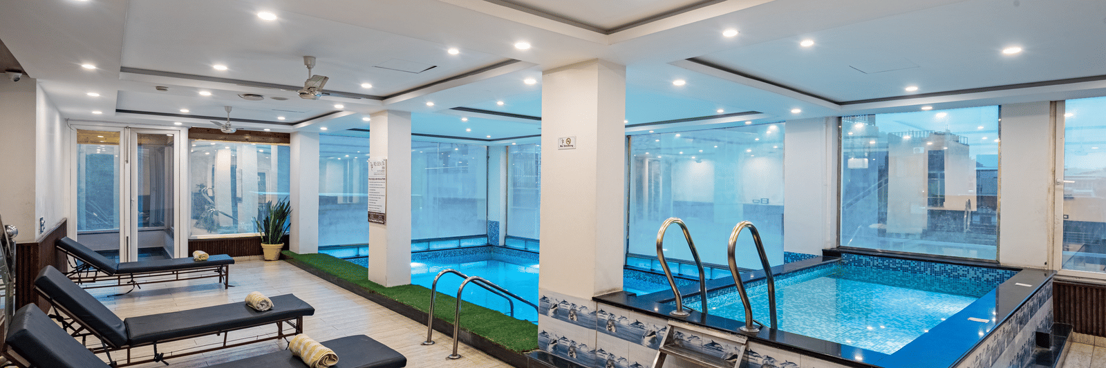 A stylish indoor pool at DLS Hotels on the Ganges Rishikesh with lounge chairs modern decor and a serene atmosphere providing a soothing retreat for guests looking to relax during their stay.