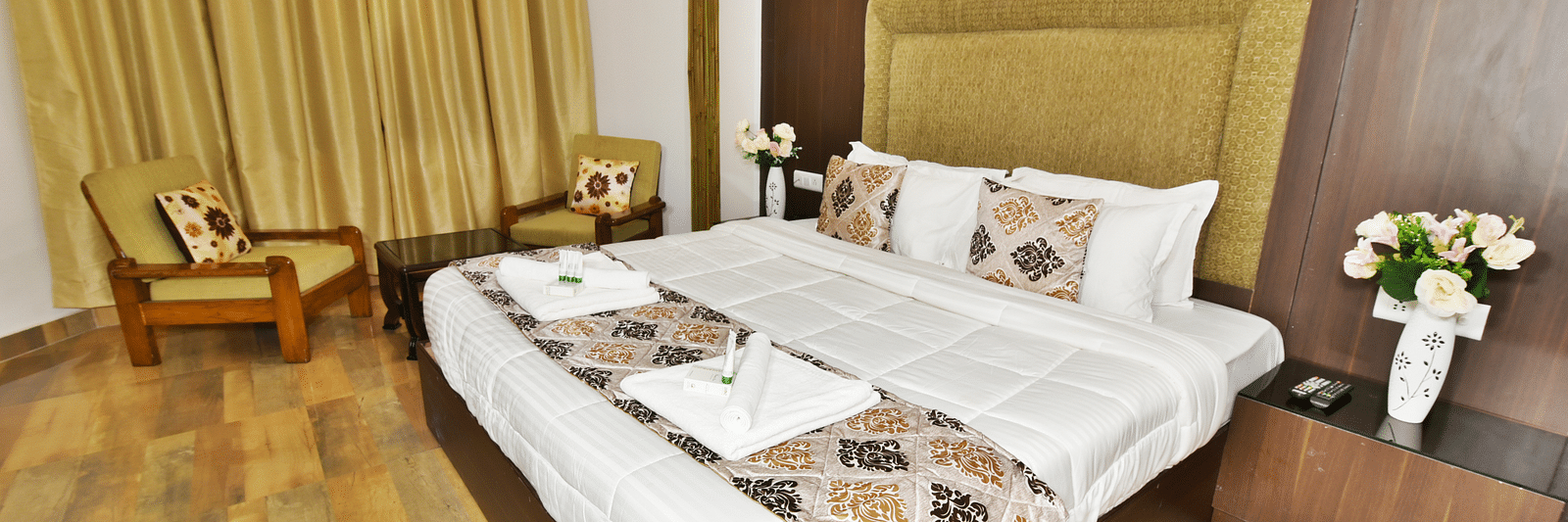 Image of the king size bed in a well furnished woodden floored room | DLS Kapoor Resort Manali