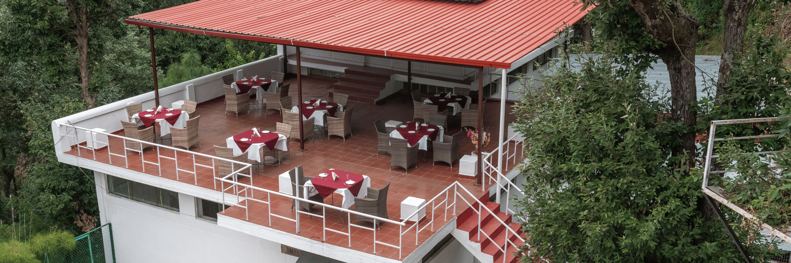 A charming outdoor restaurant at DLS Tehri Club Resort with a scenic view of the surrounding hills.