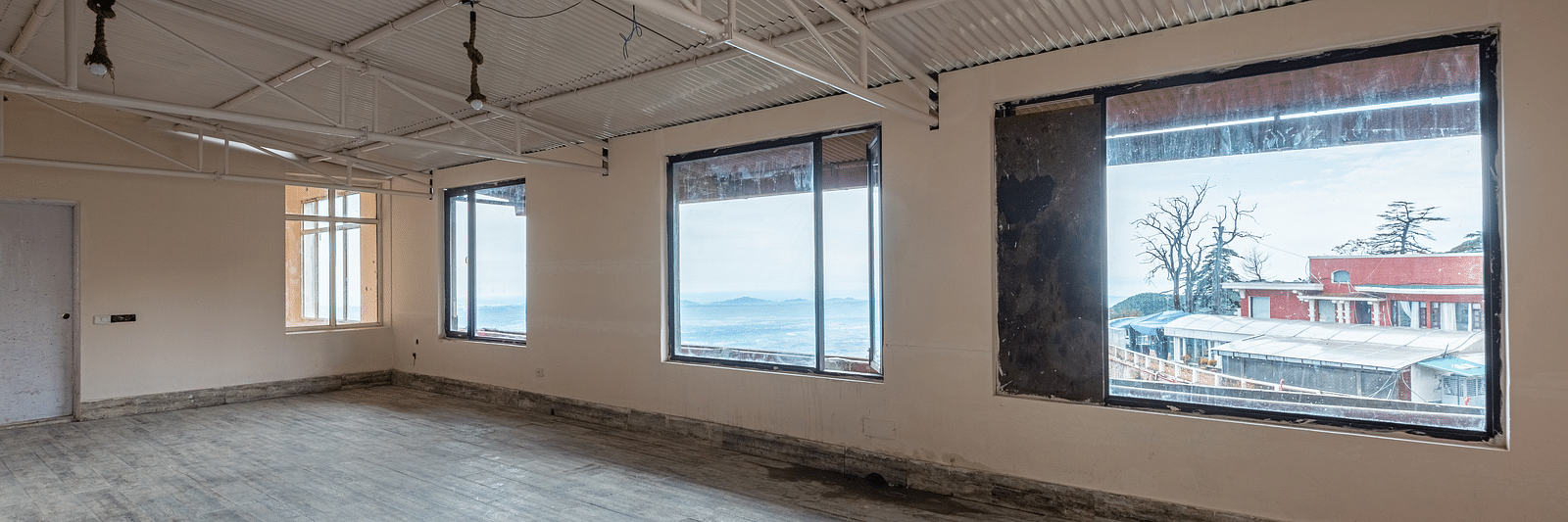 A large, empty room with high ceilings and several large windows offering views of the outdoors | DLS The Pearl