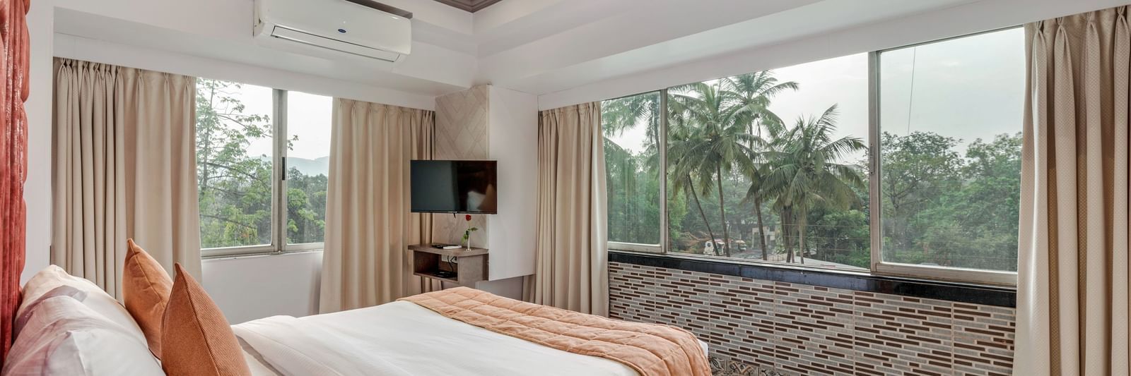 Spacious room at Emerald Retreat, Tungarli with a queen size bed, large windows, and calming garden views.