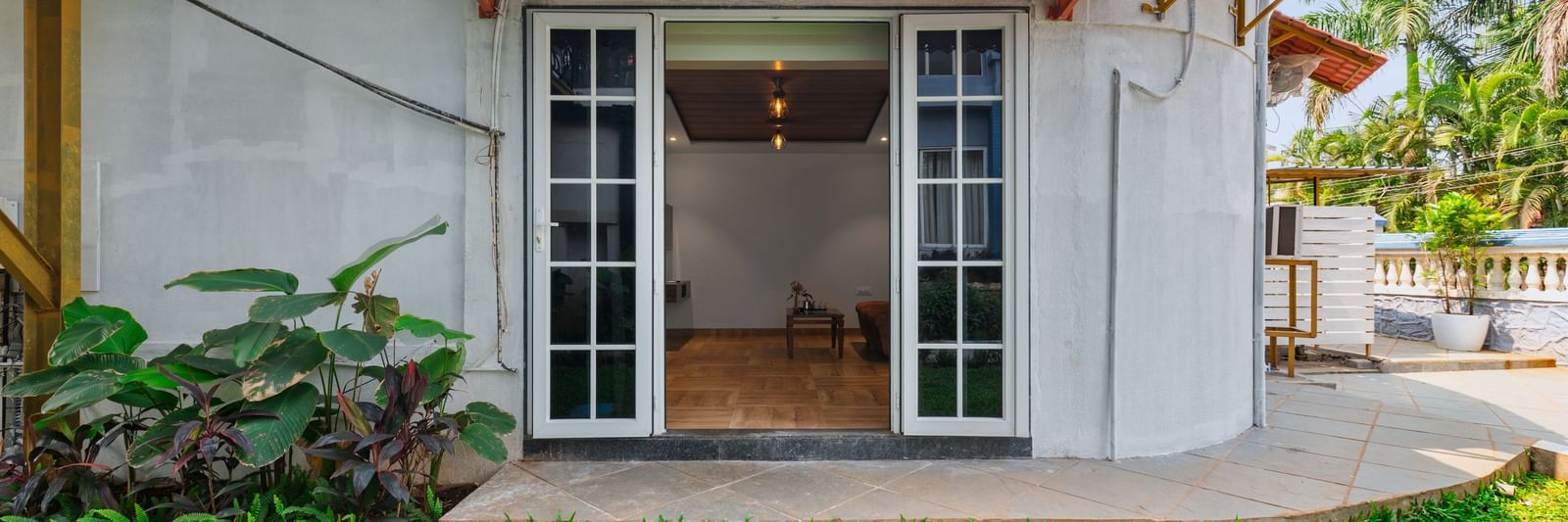 Exterior view of a villa at Mayur Retreat with a private lawn, outdoor seating, and a staircase leading to the upper balcony.