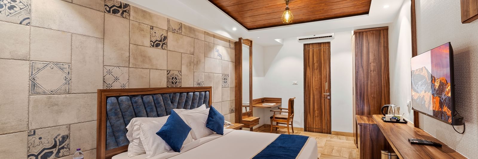 Modern bedroom with a king size bed, wooden ceiling, and stylish lighting at Mayur Retreat.