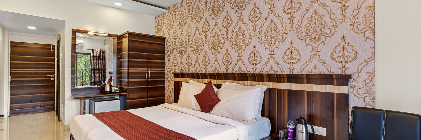 Comfortable bedroom at Mayur Retreat with two single beds, patterned wallpaper, and warm lighting.