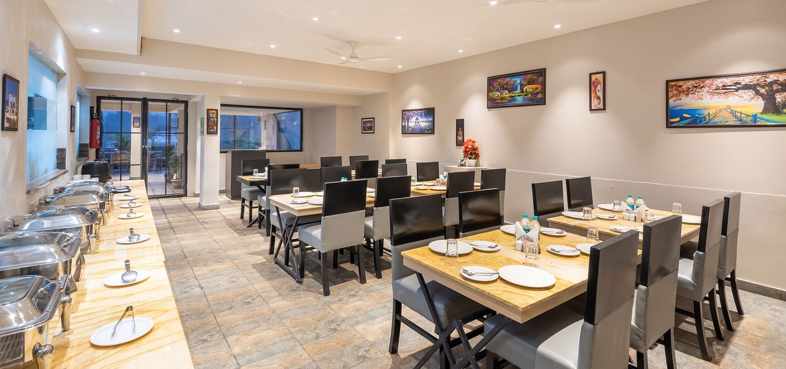 The indoor restaurant set up with chairs and tables along with a buffet table on the left at DLS Hotel Arihant, Haridwar