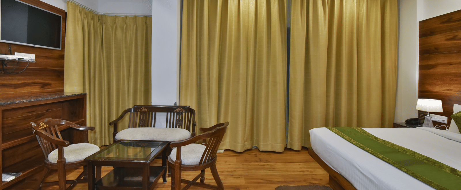 A large bed placed in front of two sofas at the Luxury Room Without Balcony at DLS Highland Resort and Spa, Mussoorie.