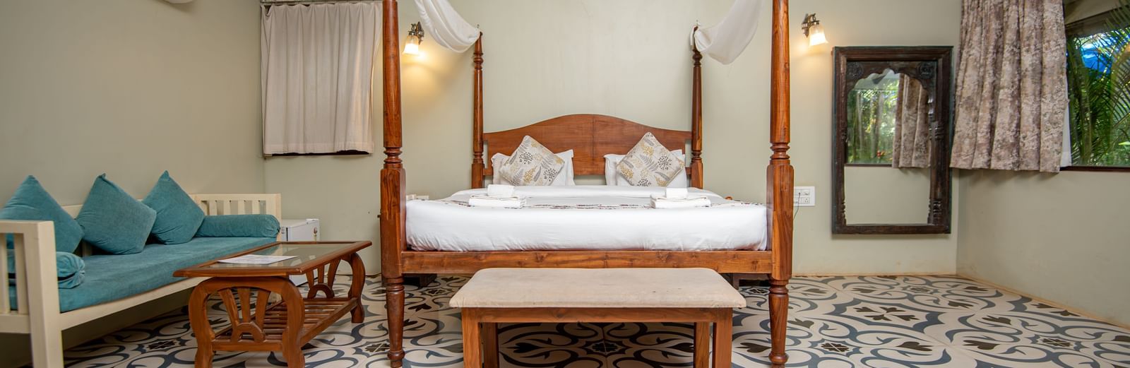 Spacious guest room with two sofas and a canopy bed under a sloped wooden roof at De Soul Santé, Morjim.