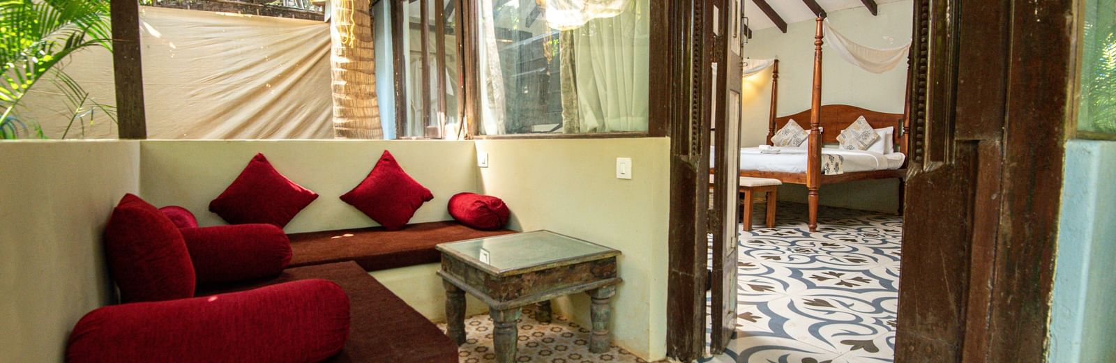 Cosy seating area in a rustic-style room with wooden elements and glass walls at De Soul Santé, Morjim.