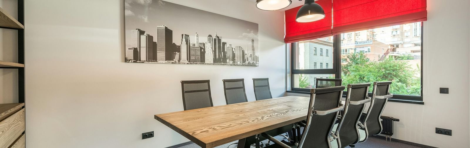 An image of a board room with chair and a table with three lights hanging from the ceiling