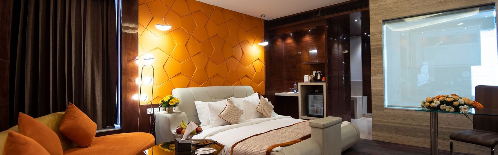 Junior Suite decked with a comfy bed and orange sofa at Hotel Park Elanza, Coimbatore