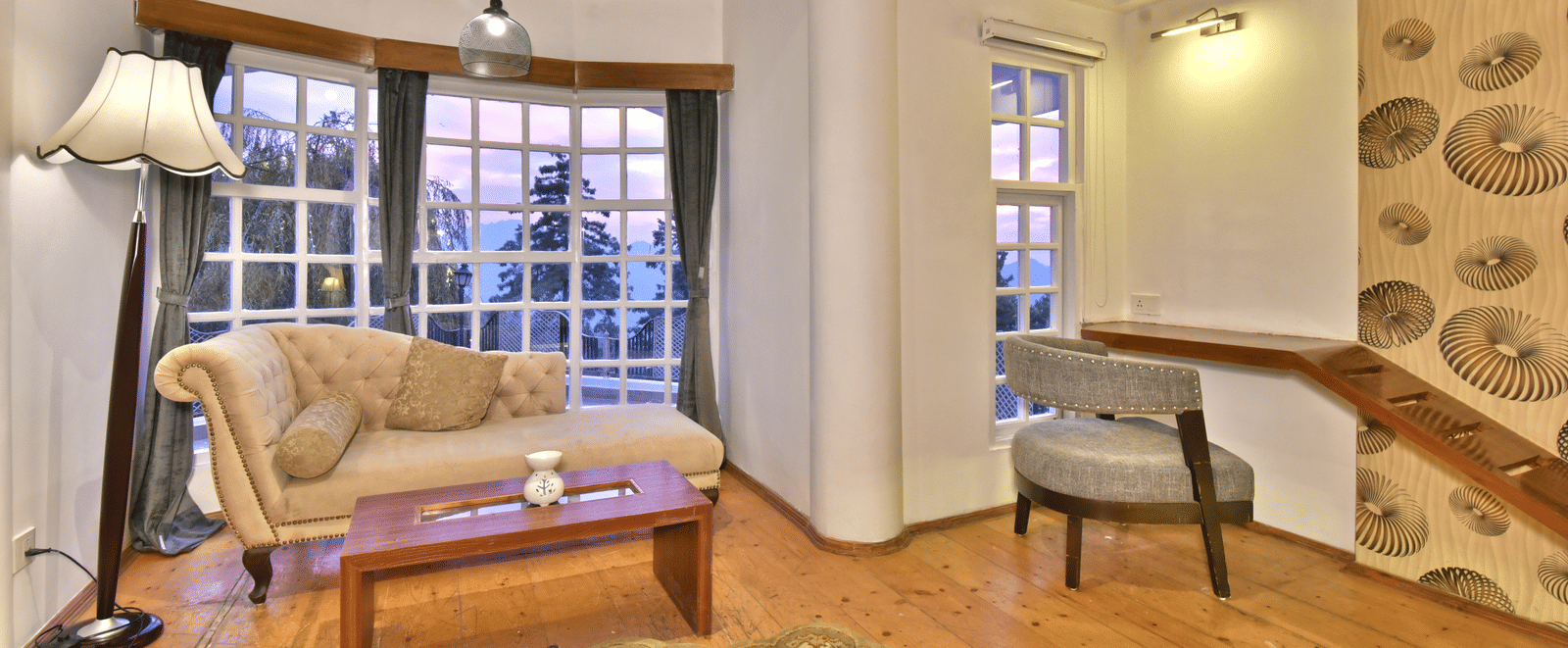 Living space of one of the suite rooms in Mashobra featuring sofas and a chair with fancy light hanging from the ceiling at DLS Hillcrest Resort, Shimla.
