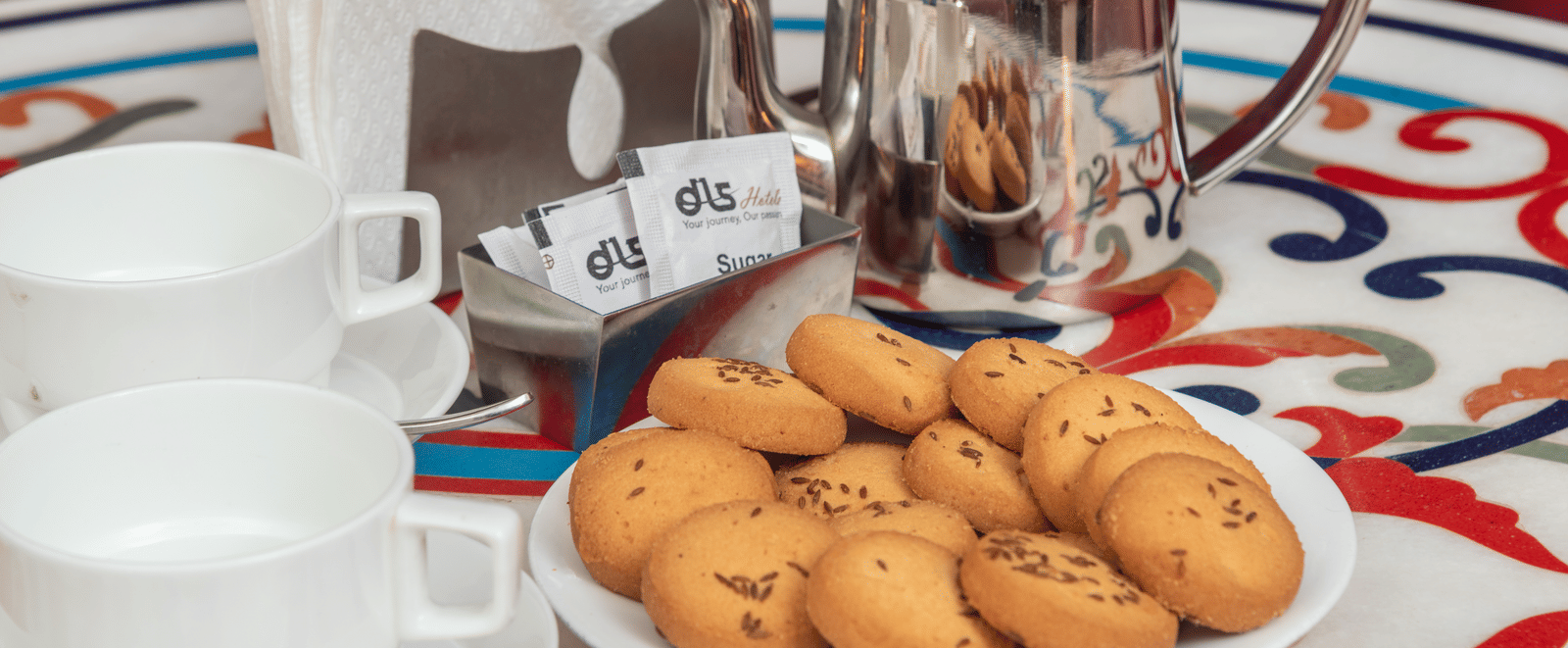 A table set with cookies, tea pot and two cups at DLS Hotels On The Ganges.
