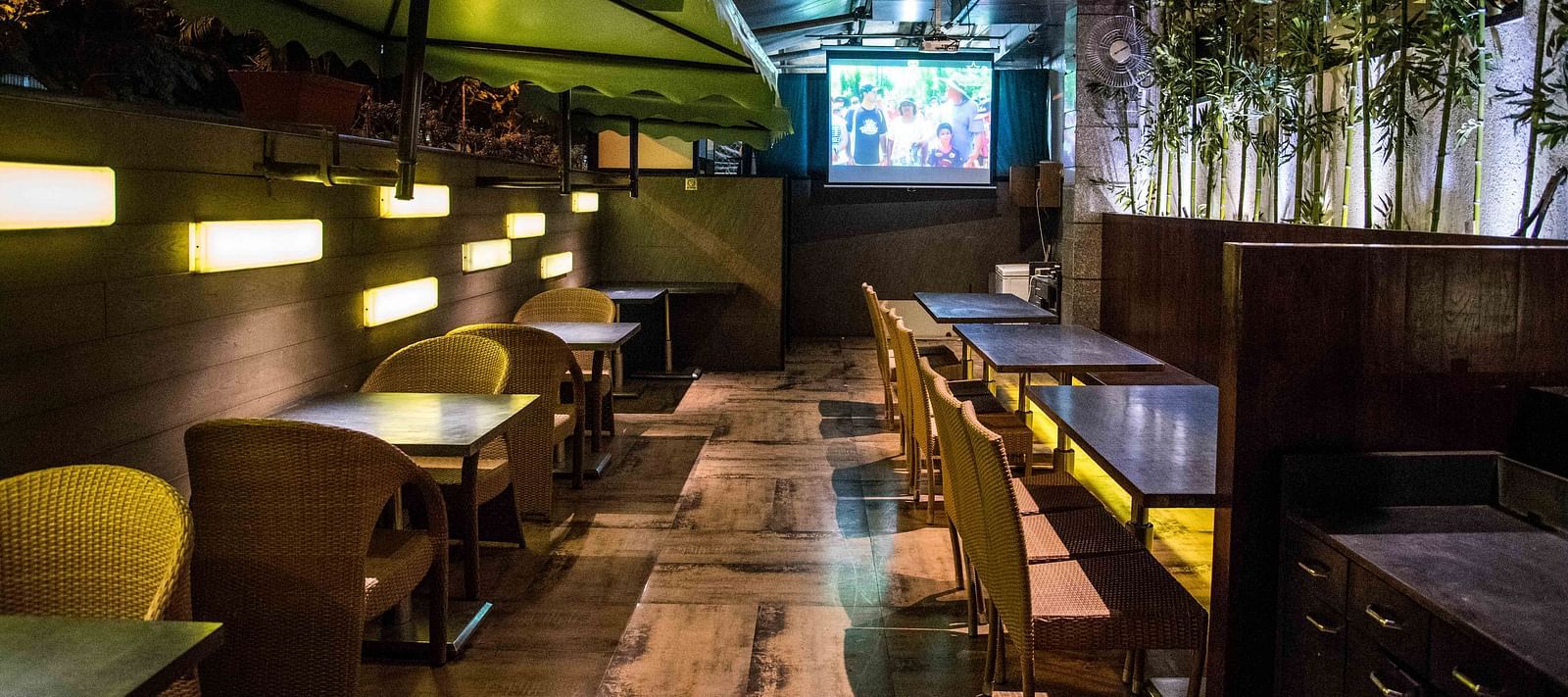 Modern restaurant featuring wooden chairs, tables, and a wall with plants hanging as decoration at Oriental Aster, Mumbai.