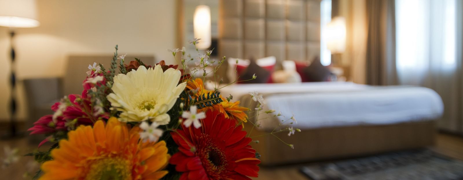 Close-up shot of a vibrant flower vase filled with colorful blossoms placed in a suite at The Manor, Bareilly, 