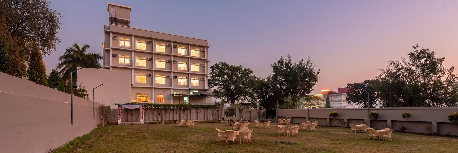Lawn area of the lawn area at DLS Park Grace, Haridwar featuring featuring multi storey building, seating area, purple sky and beautiful green lawn.