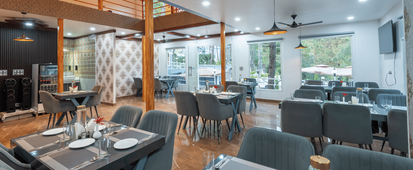 A contemporary restaurant area with neatly set tables, cushioned chairs, ceiling fans, and large windows providing natural light - DLS Nature Trinket Resort, Dalhousie