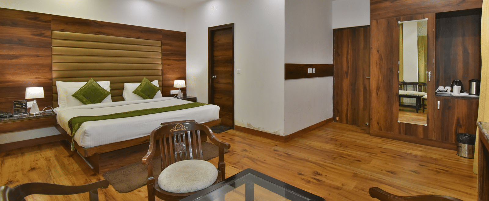 A large bed placed in front of two sofas at the Luxury Room Without Balcony at DLS Highland Resort and Spa, Mussoorie.