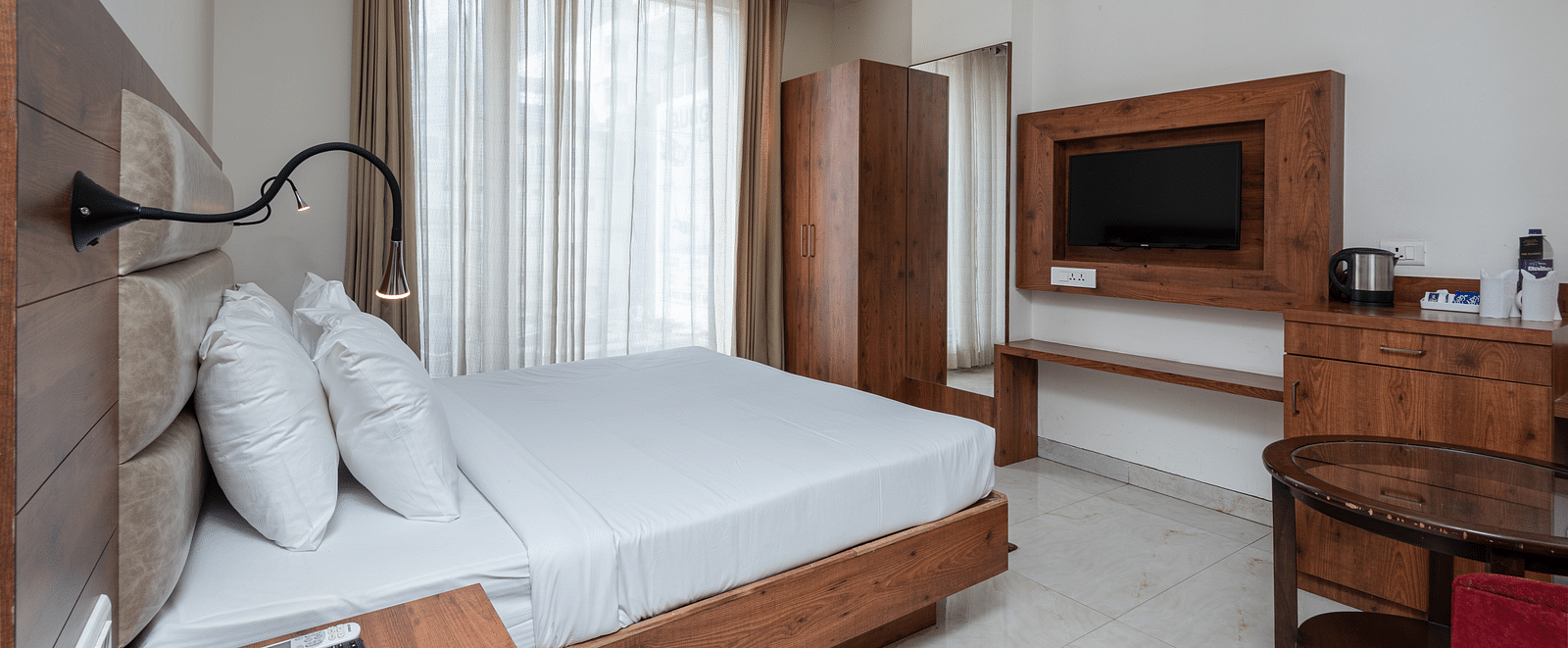 Side view of a Deluxe Room featuring a TV mounted on the wall and a ceiling fan overhead, at DLS The Classio