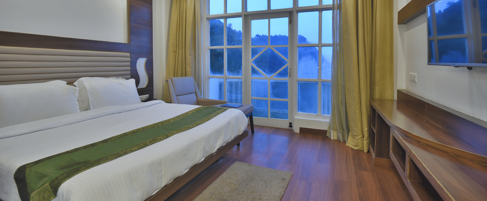 A view of a large bed next to a large bed in Premium Room at DLS Highland Resort and Spa, Mussoorie.