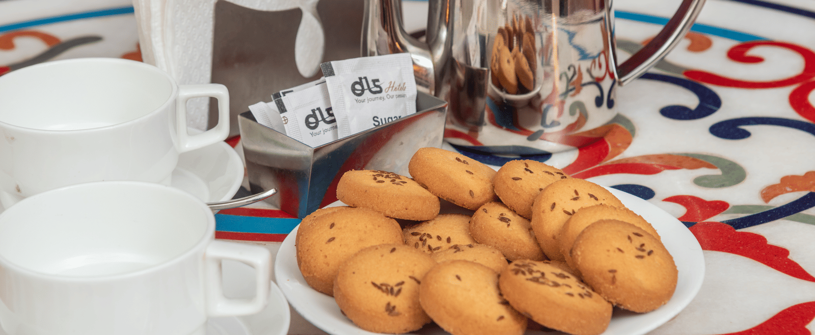 A table set with cookies, tea pot and two cups at DLS Hotels On The Ganges.