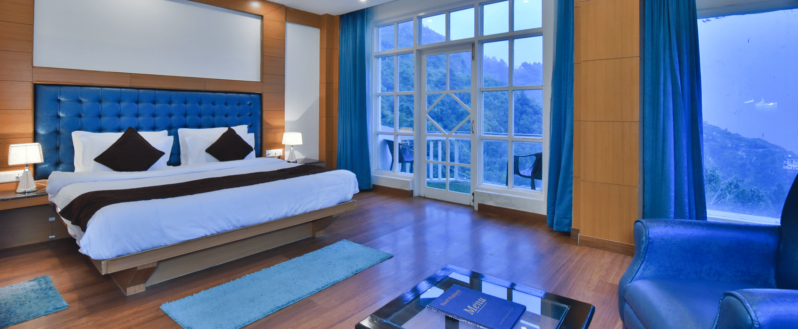 A large bed placed in front of the sofas in Luxury Room with Balcony at DLS Highland Resort and Spa, Mussoorie.