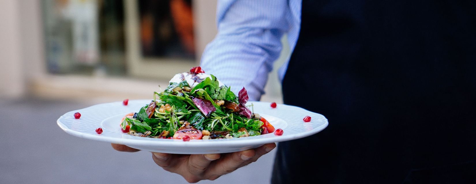 A person holding a plate of salad