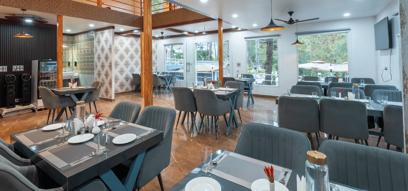 A contemporary restaurant area with neatly set tables, cushioned chairs, ceiling fans, and large windows providing natural light - DLS Nature Trinket Resort, Dalhousie