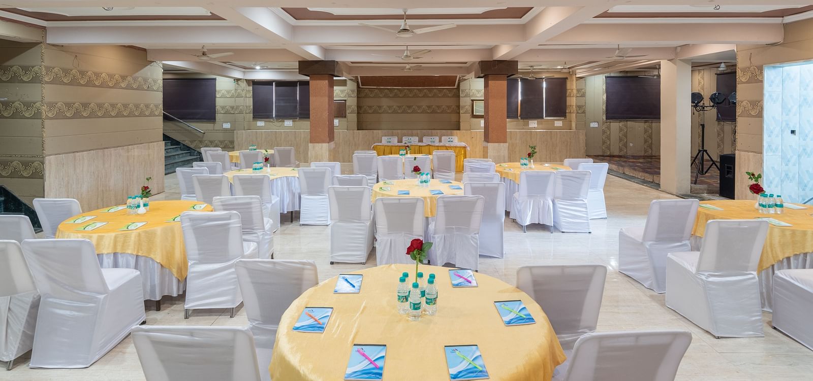 Banquet hall with round tables and chairs at DLS Park Grace, Haridwar.