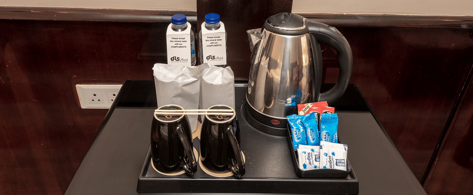 Tea and coffee maker with sugar, beverage sachets, and a kettle at DLS Park Grace, Haridwar.