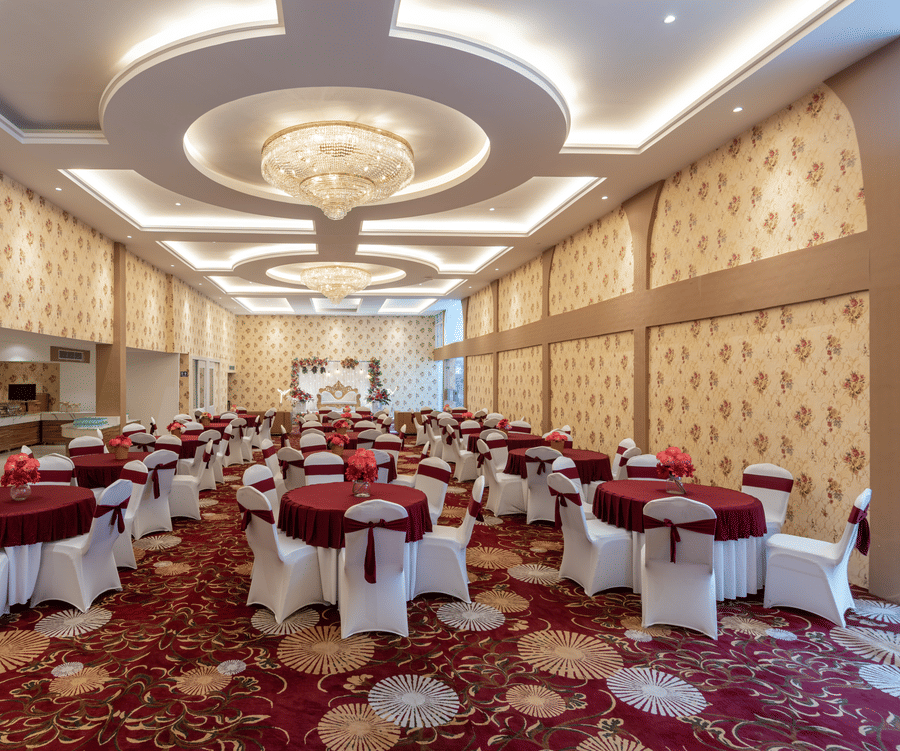 Banquet hall set up with round tables in maroon and white linen at Mango Grove Hotel.