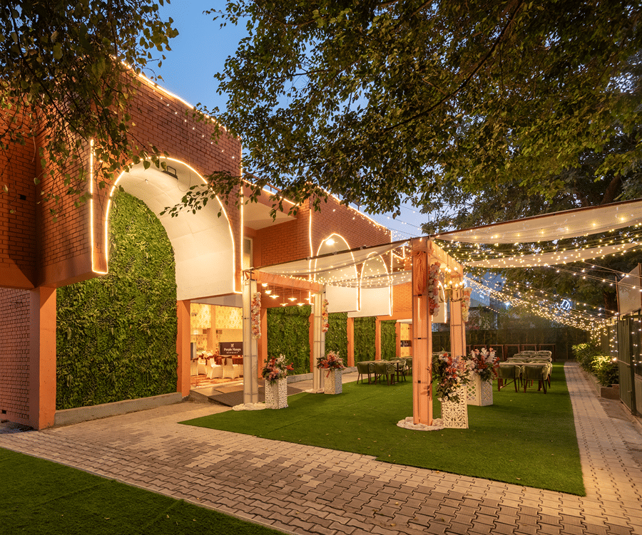 Decorative entrance archway with greenery and trees leading into the property at Mango Grove Hotel.