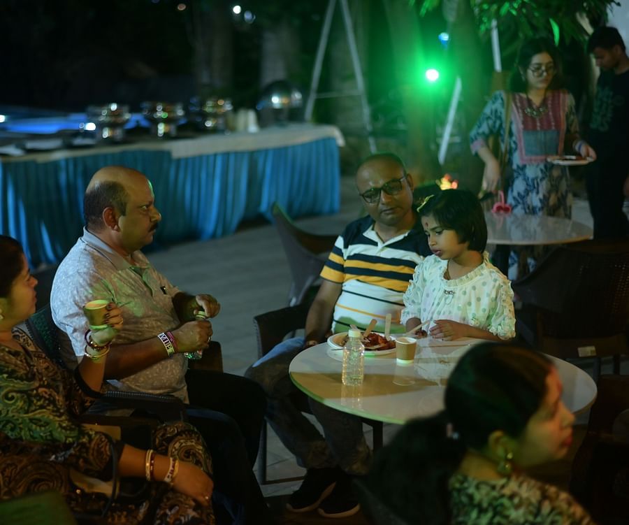 Event space featuring few people enjoying different beverages, with a buffet area featuring on the side and round tables at Rangamati Garden Resort.