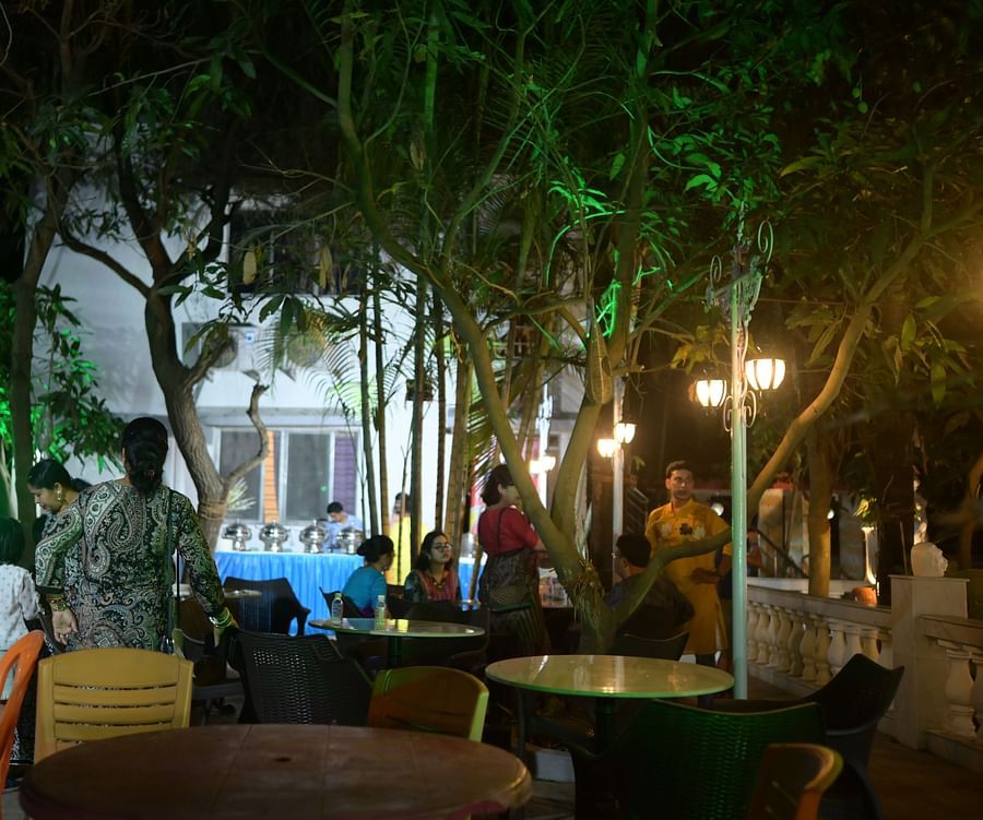 Event space featuring ample seating area with round tables and people roaming around at Rangamati Garden Resort.