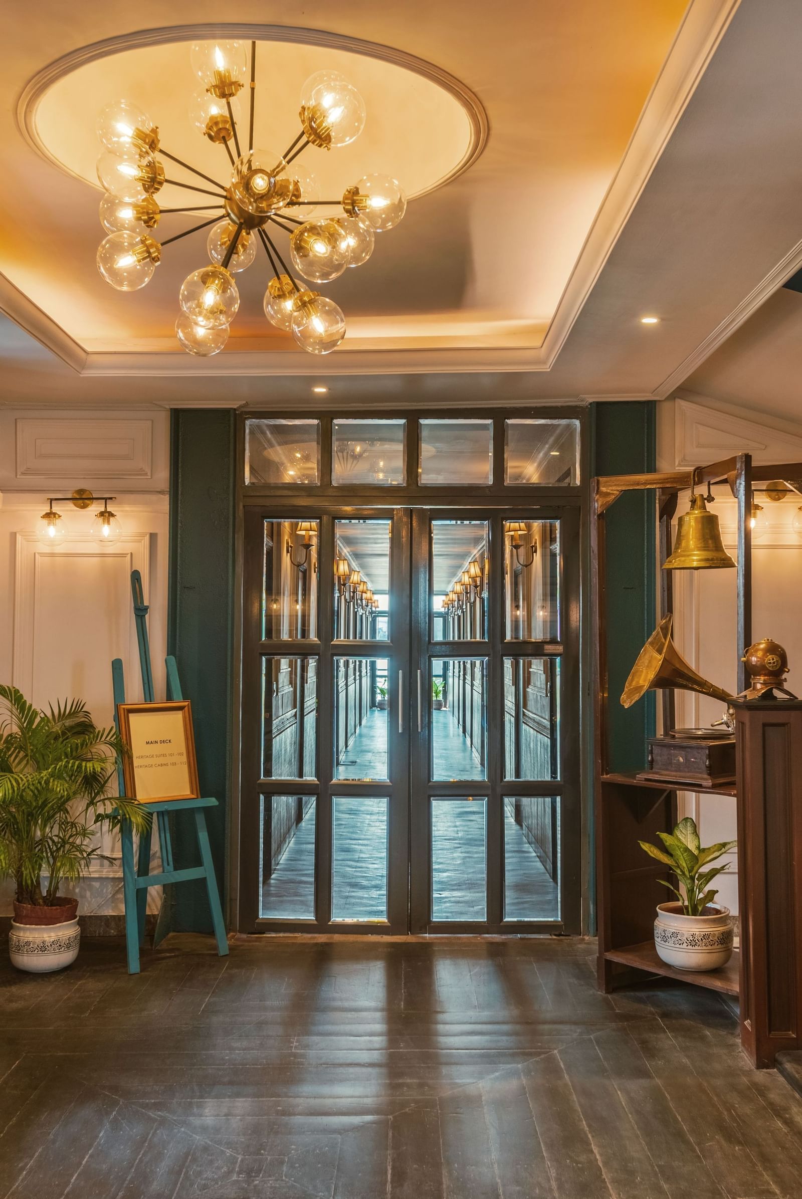 The elegant lobby or main staircase entrance at Polo Floatel Kolkata. The space is lit by a modern chandelier and features a staircase, classic doors, and polished floors.