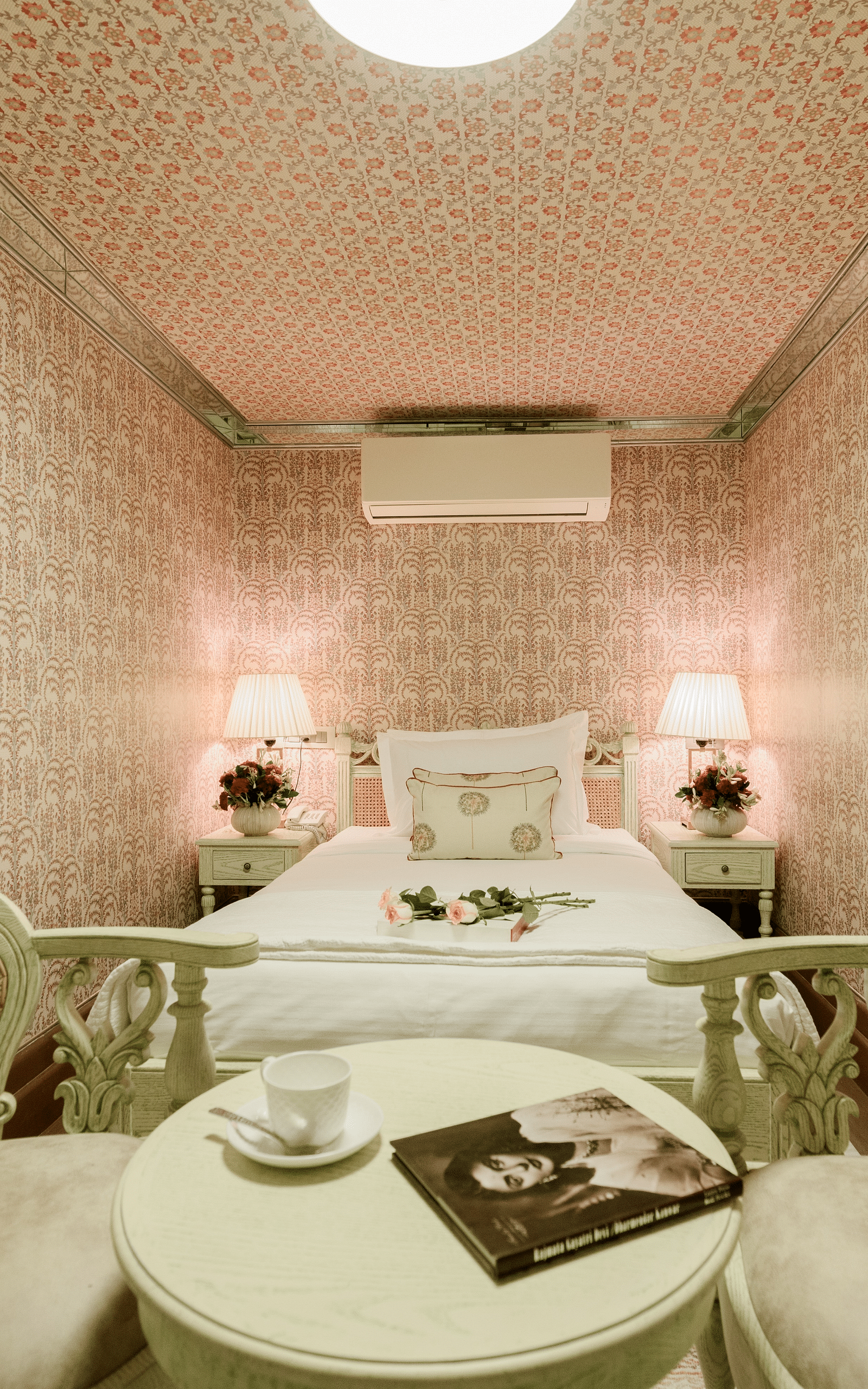 Lavish room at Surya Haveli in Jaipur featuring a sitting space with two couches and a coffee table with a magazine on it and a plush bed in the background