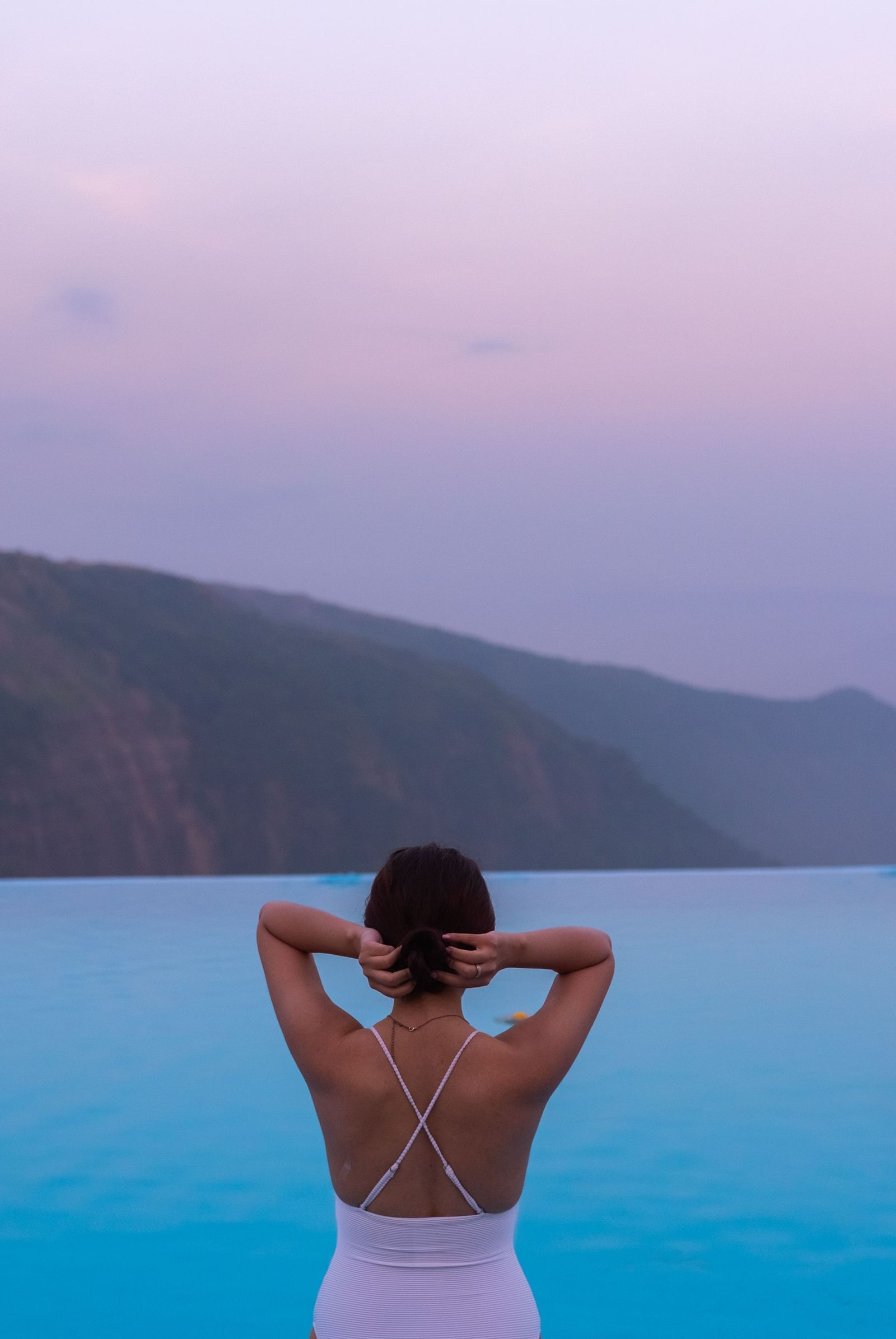 A back view of a guest in the infinity pool with a valley view at Polo Resort Cherrapunjee.