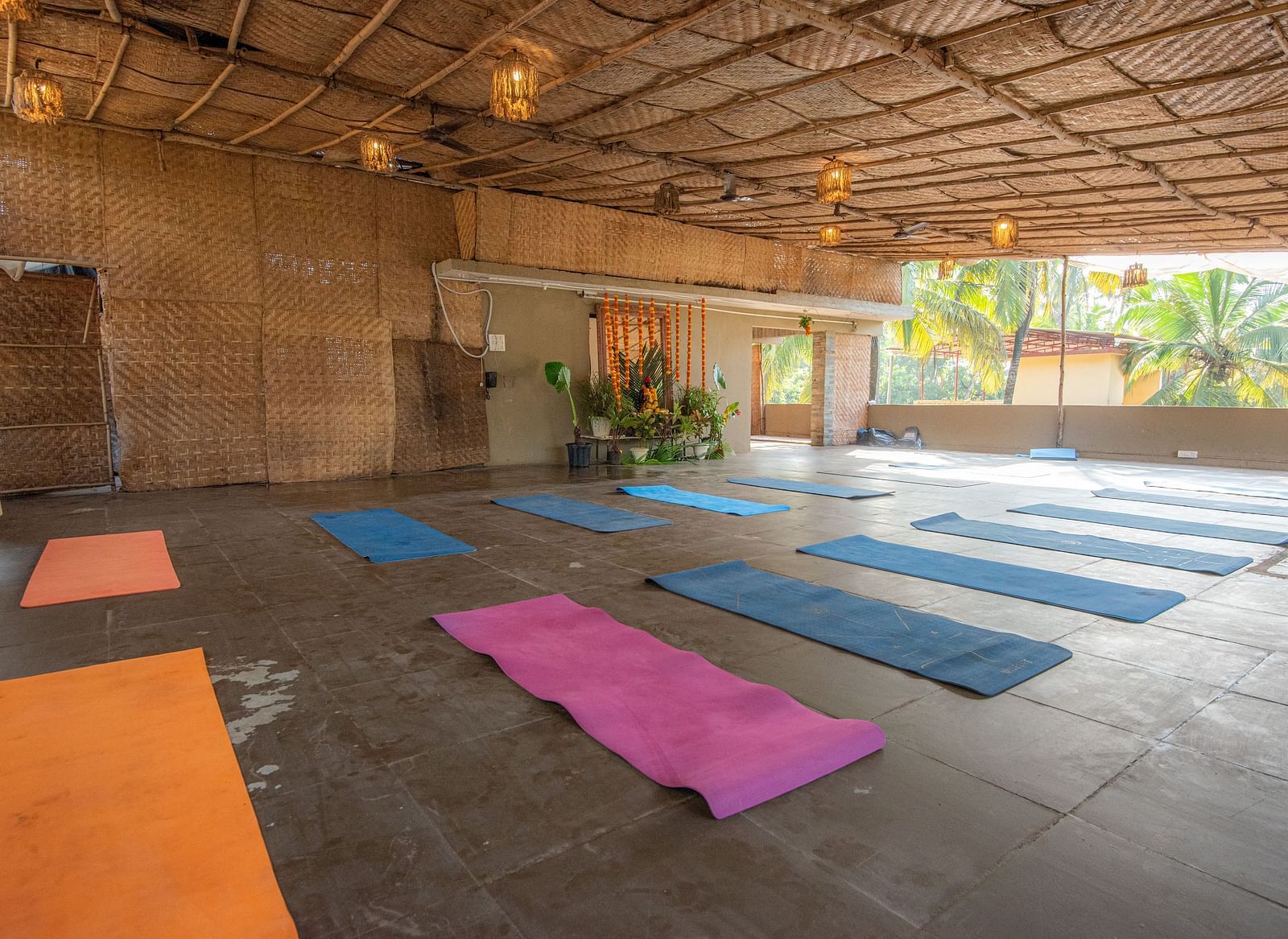 Spacious indoor yoga hall with colourful mats laid out on the floor at De Soul Santé, Morjim