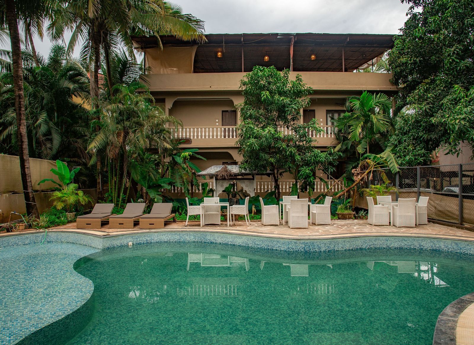 Outdoor swimming pool area with sun loungers and lush greenery at De Soul Santé, Morjim