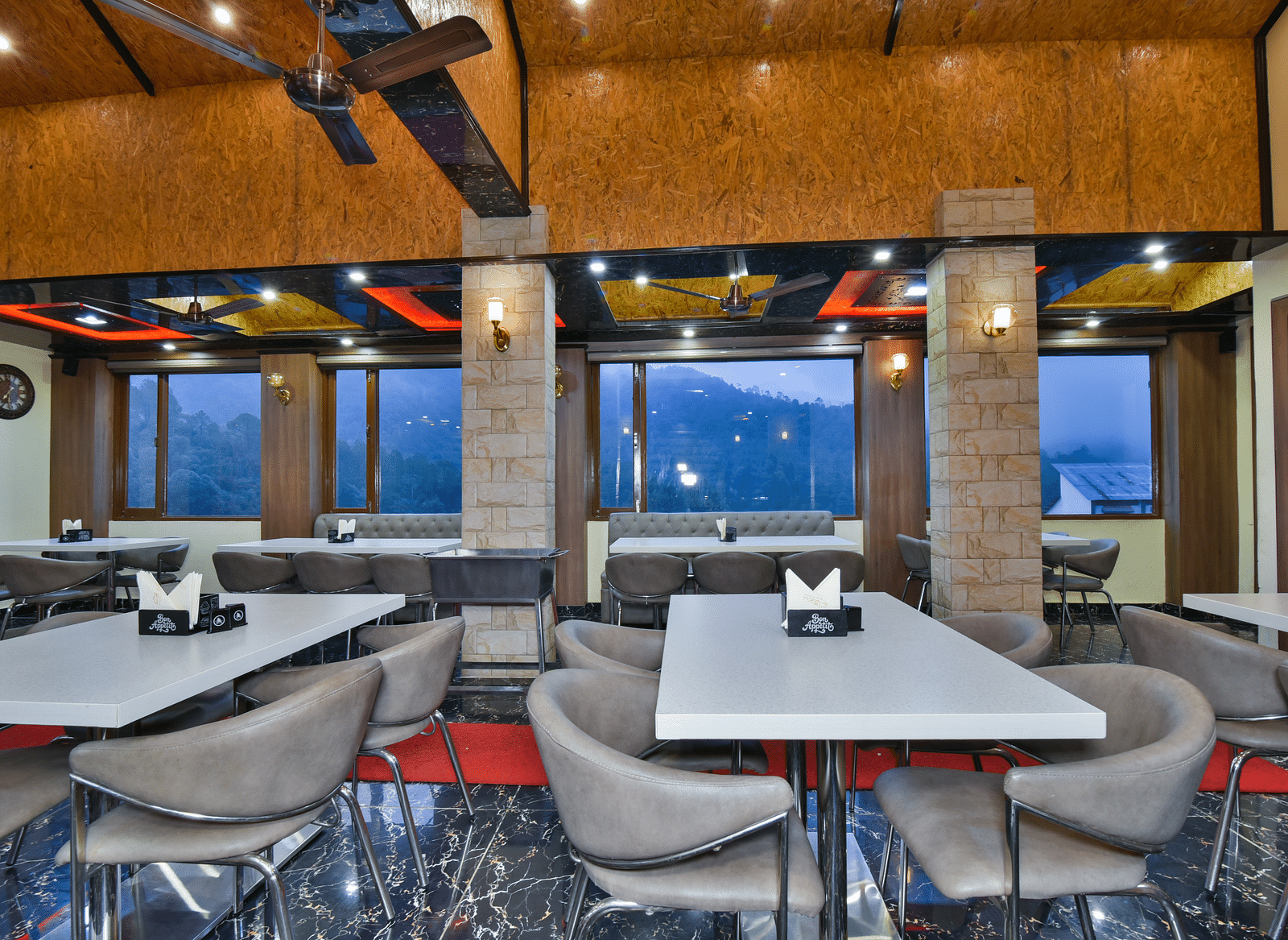 Restaurant at DLS Dalhousie Valley Resort with chairs, tables, ambient lighting and serene views