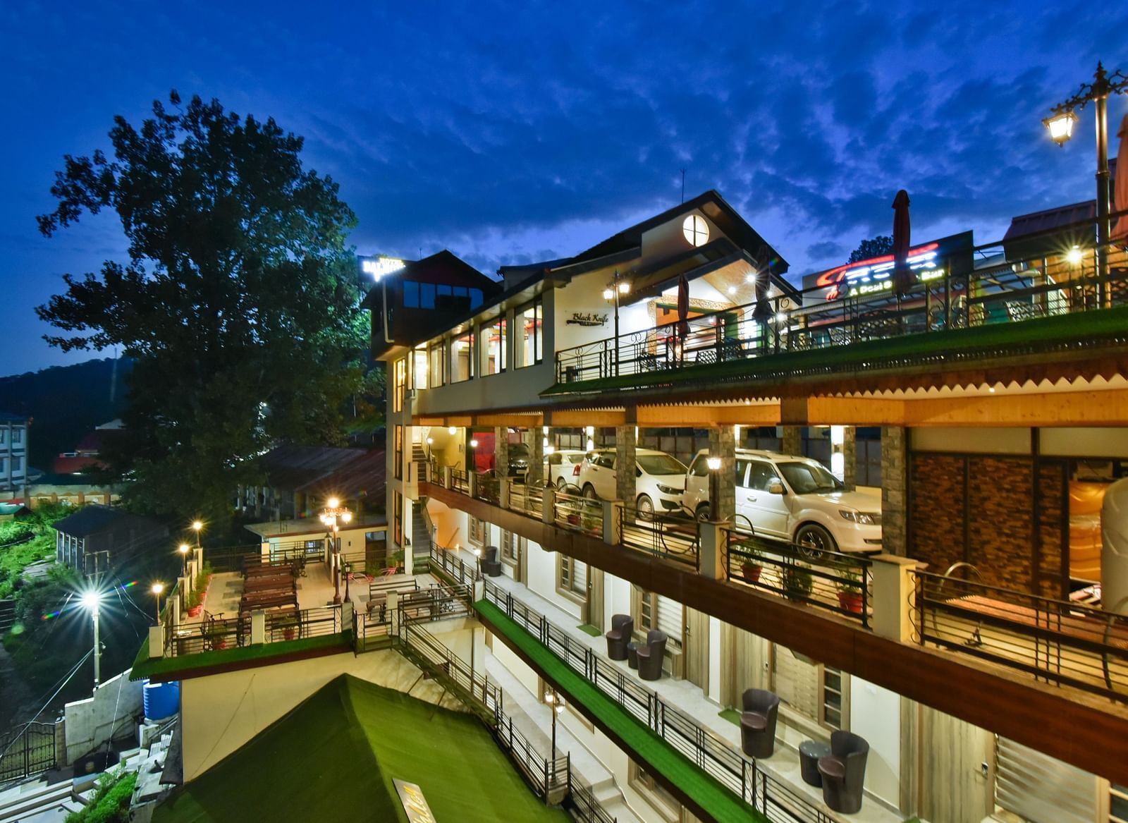 Facade image of DLS Dalhousie Valley Resort taken at night with warm lighting featuring parking area as well.