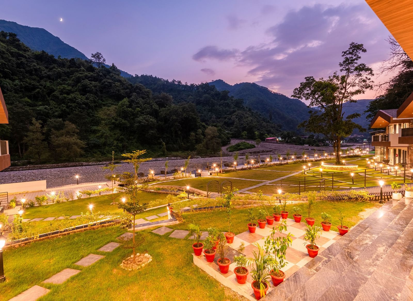 Garden area at DLS Divine River Resort and Spa featuring lush green grass and flower pots.