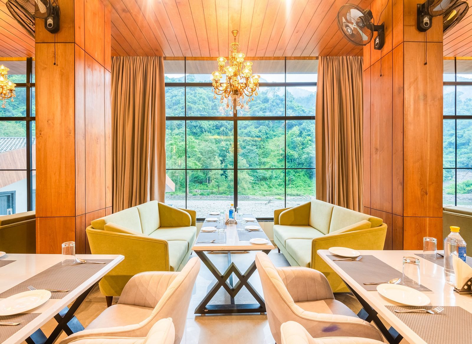 Restaurant at DLS Divine River Resort and Spa  with seating arrangement, large window, chandelier, and ambient lighting. 