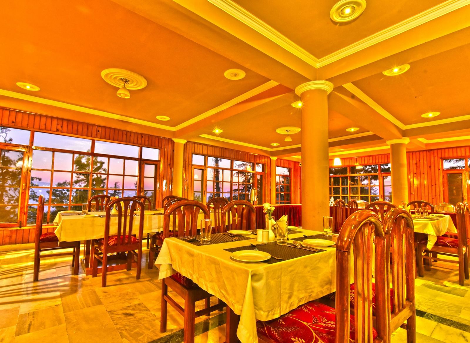 Restaurant with chairs, tables, and cutlery set up at DLS Hillcrest Resort, Shimla.